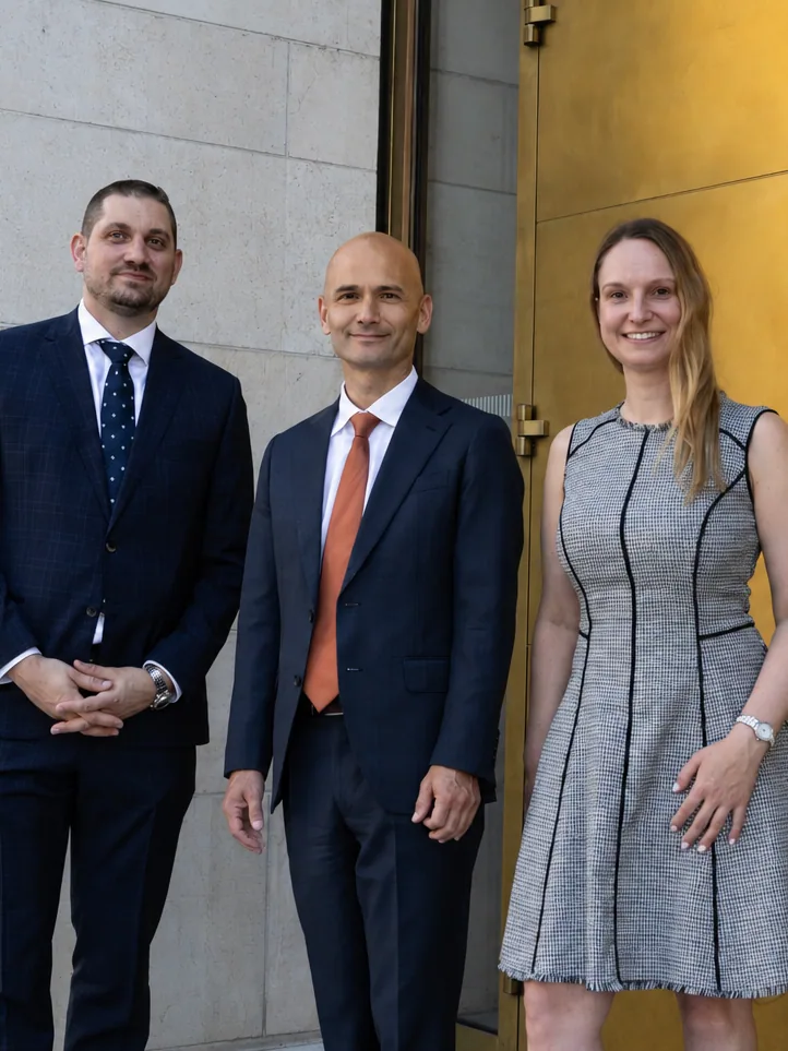 Three members of the CONSAVO team at the golden entrance door in Zurich